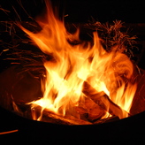 A campfire burns in a contained metal fire pit.