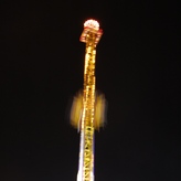A close-up photo of a lit-up carnival ride at night.