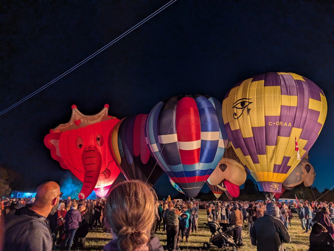 Six hot air balloons lit up against a night sky.