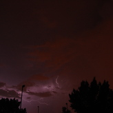 A nighttime sky with scattered clouds and lightning bolts illuminating the darkened landscape.