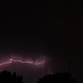 A bright, jagged lightning bolt illuminates the dark night sky.