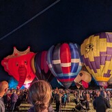 Six hot air balloons lit up against a night sky.